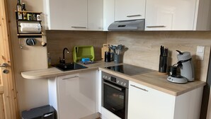 A compact kitchen with white cabinets, a Bosch oven, a coffee maker, and a sink with a faucet.