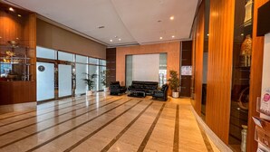Un hall d’entrée spacieux avec un sol en marbre, un coin salon avec des canapés et un comptoir de réception.
