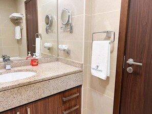 Un baño con dos lavamanos, un espejo, un perchero para toallas y una puerta.