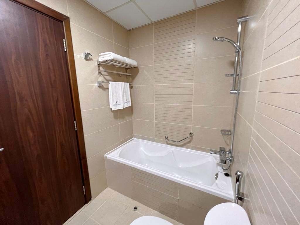 A bathroom with a bathtub, toilet, and a towel rack.