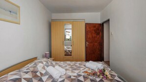 A bedroom with a bed, a wooden wardrobe, a wooden door, and a framed picture on the wall. - Lovely House Luiza (Tar-Vabriga)