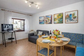 Un salon comprenant un téléviseur, un canapé, une table à manger et des œuvres d’art accrochées au mur.