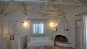 A cozy room with a sofa, a wooden table, and a fireplace. - Likavgies Comfort Maisonettes (Alonissos)