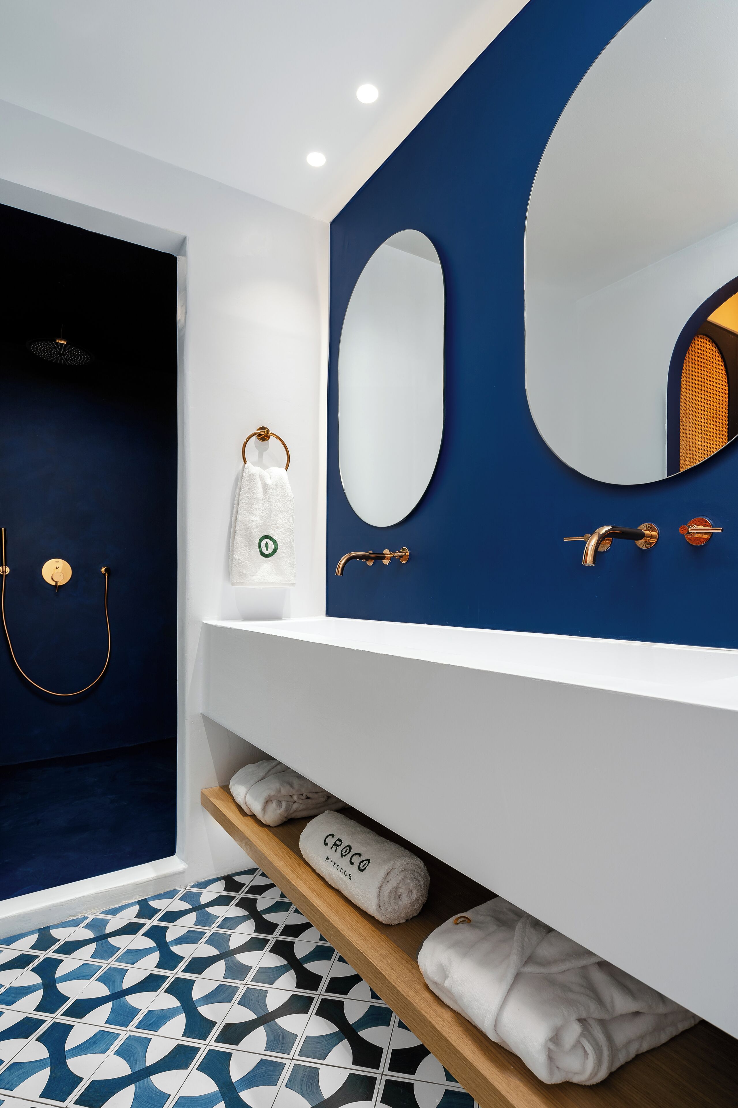 A modern bathroom with a blue accent wall, a white sink, and a large mirror.