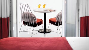 A room with a bed, a round table with two chairs, and a view of the sea. - Croco Mykonos (Mykonos)