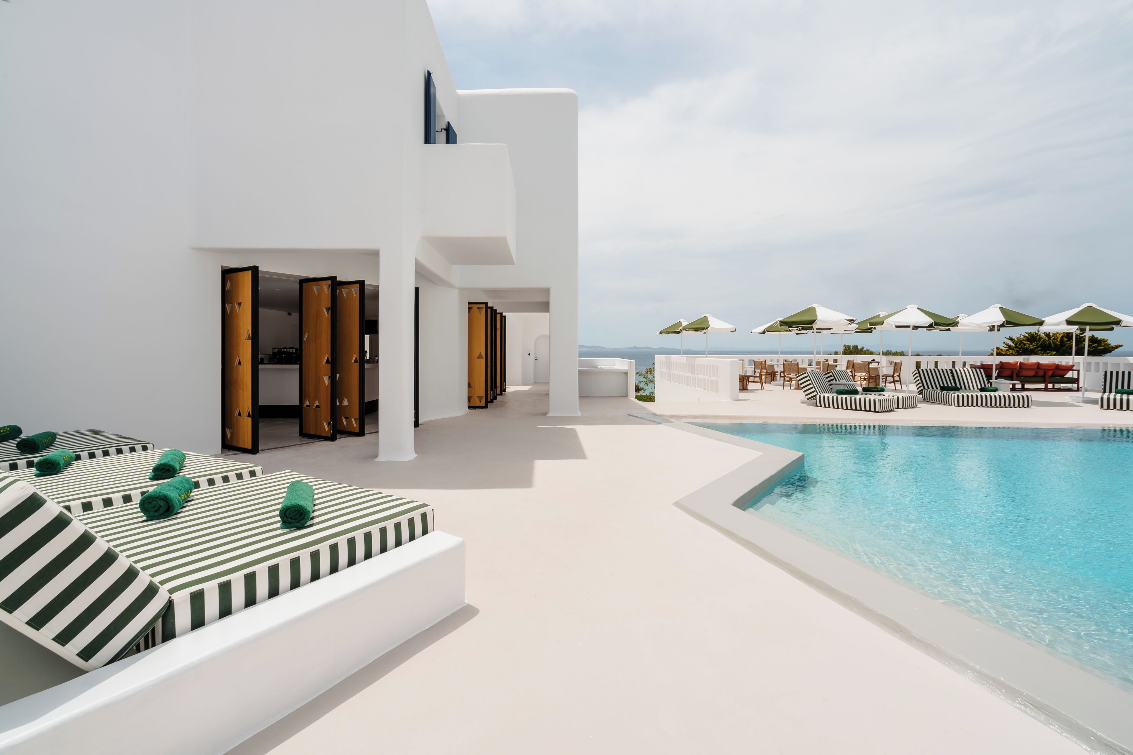 A modern poolside area with lounge chairs and a pool, overlooking a scenic view.