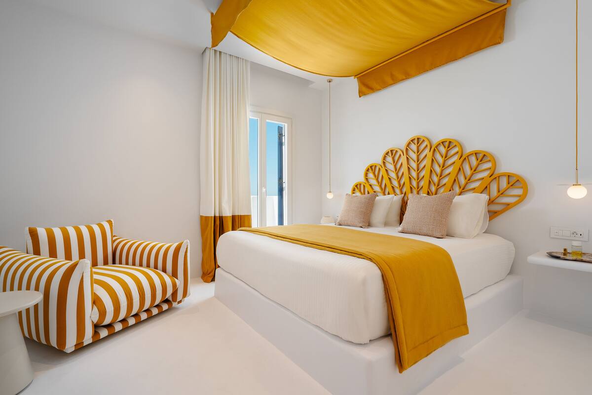 A modern bedroom with a large bed, a sofa, and a nightstand.