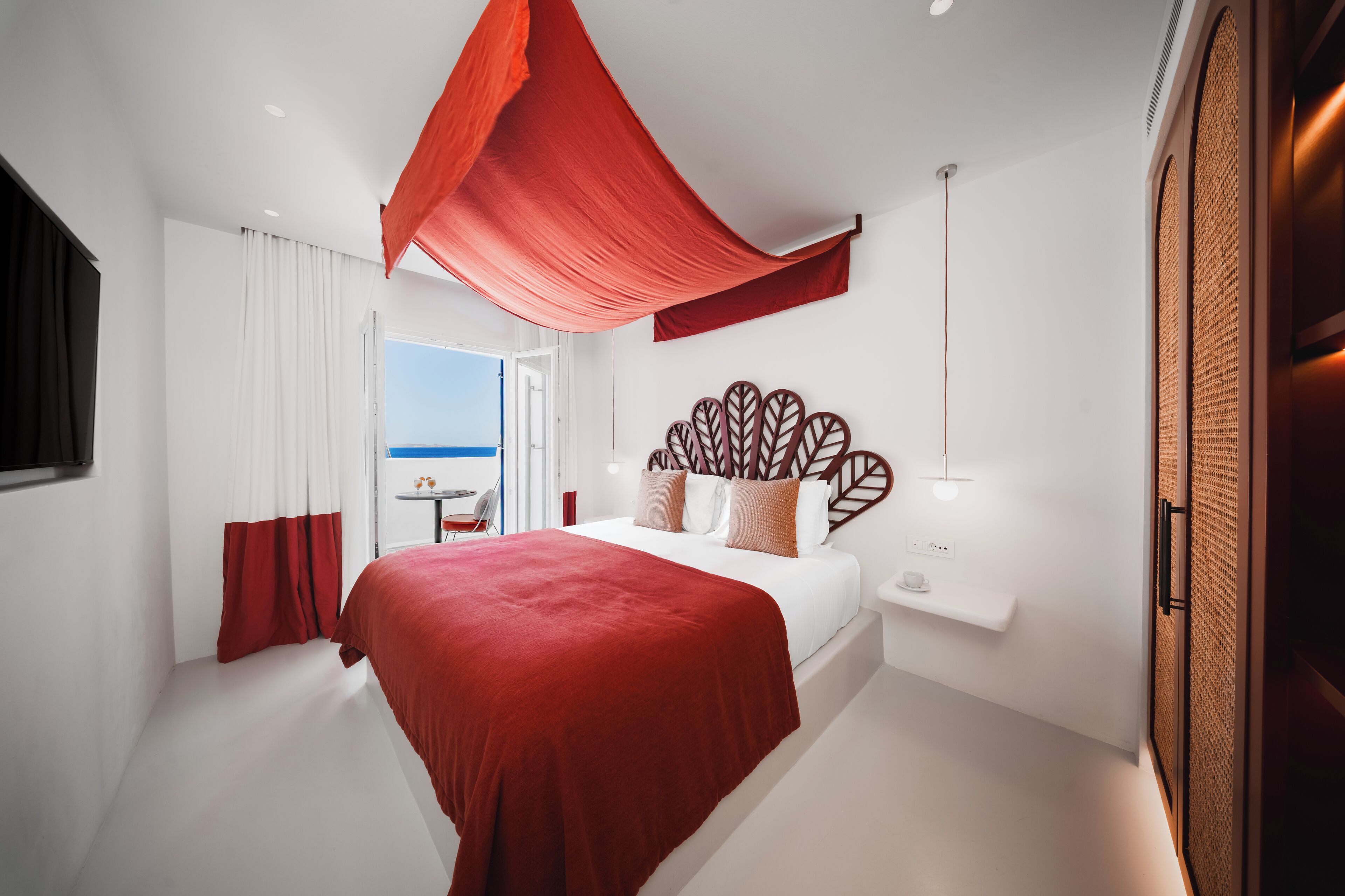 A modern hotel room with a large bed, a view of the sea, and a balcony.