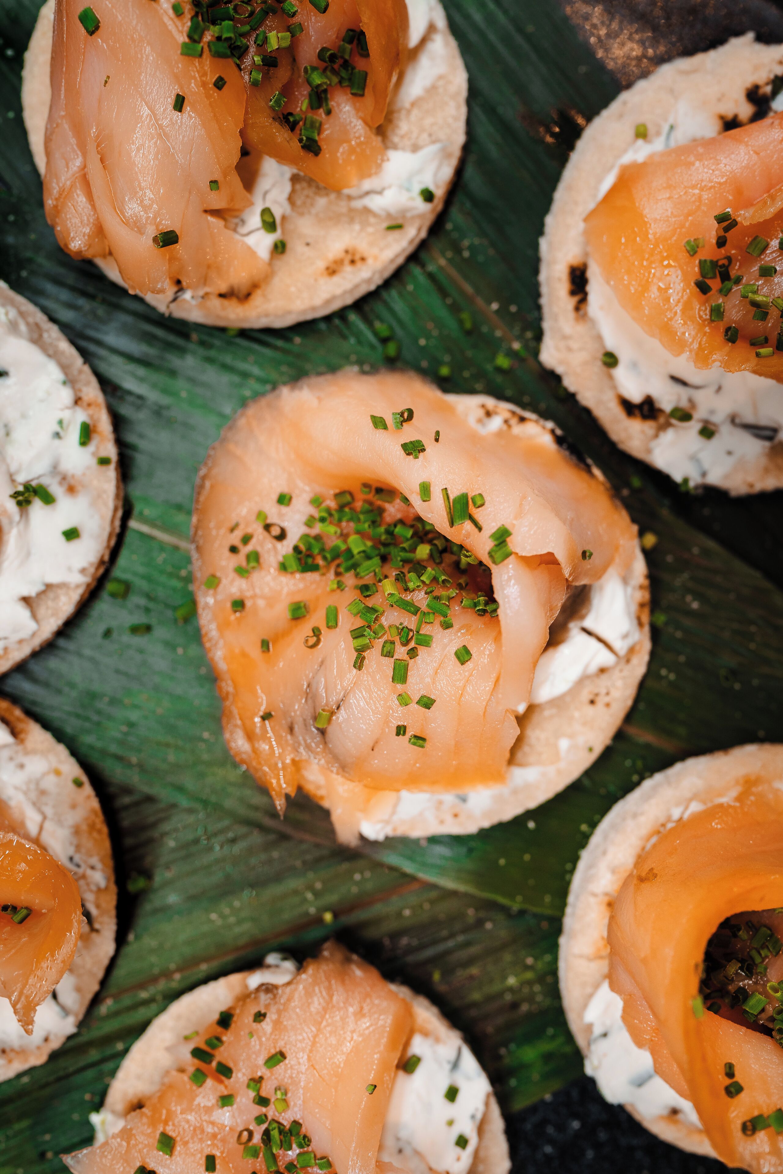 A close-up of bagels with cream cheese and smoked salmon garnished with chives.