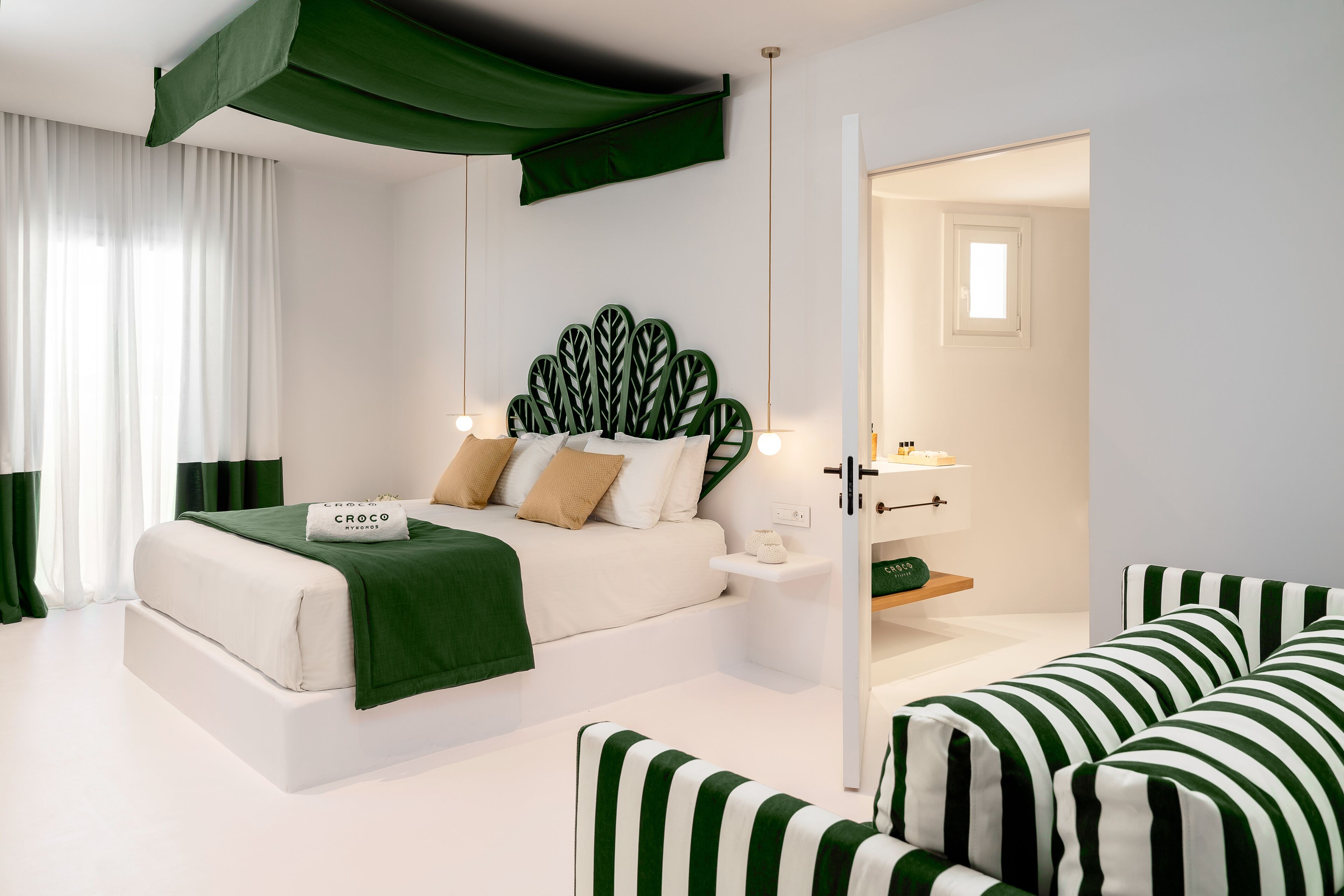 A modern bedroom with a bed, green-striped sofa, and a unique leaf-patterned headboard.