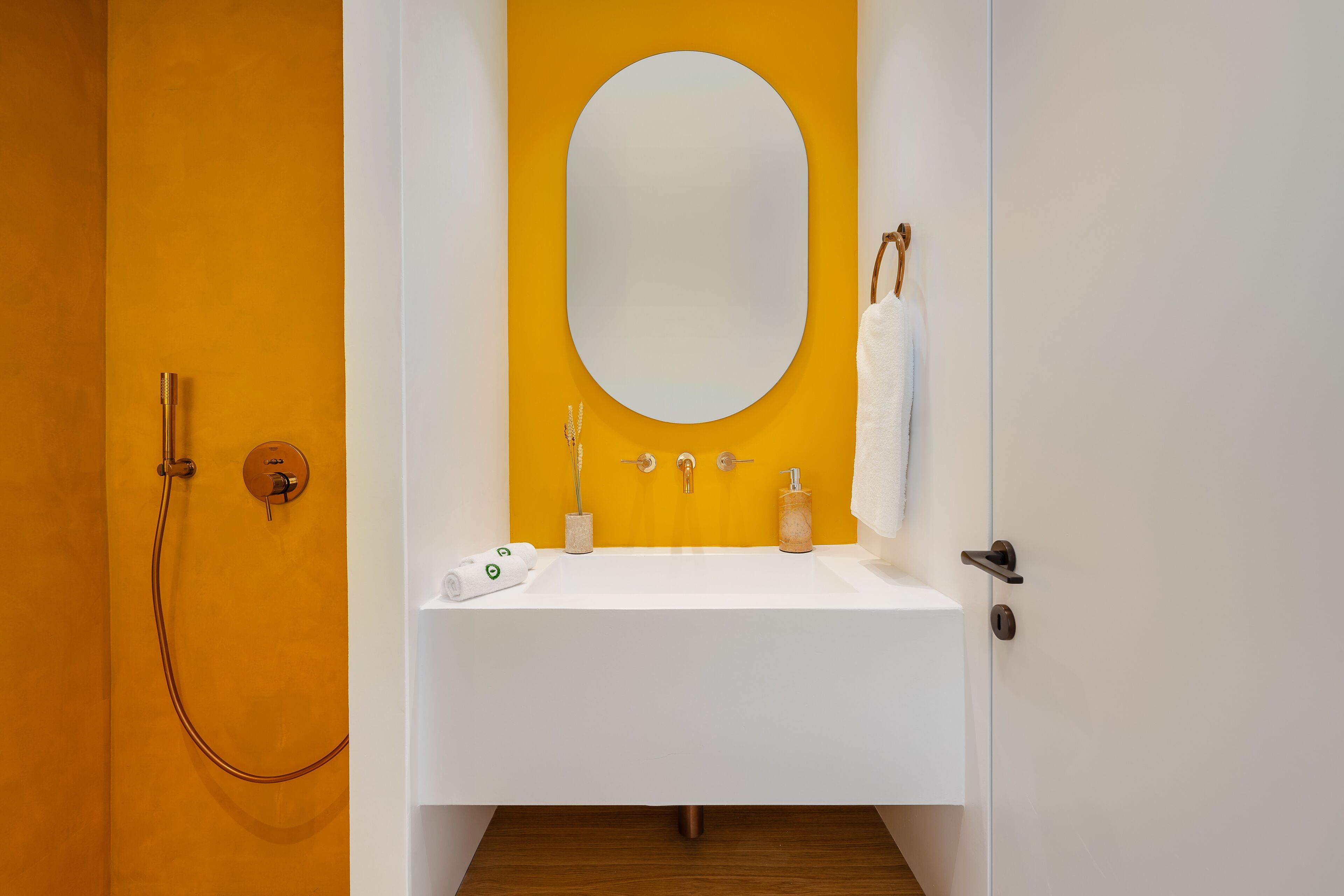 A bathroom with a white sink, a large oval mirror, and a shower.