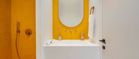 A bathroom with a white sink, a large oval mirror, and a shower.