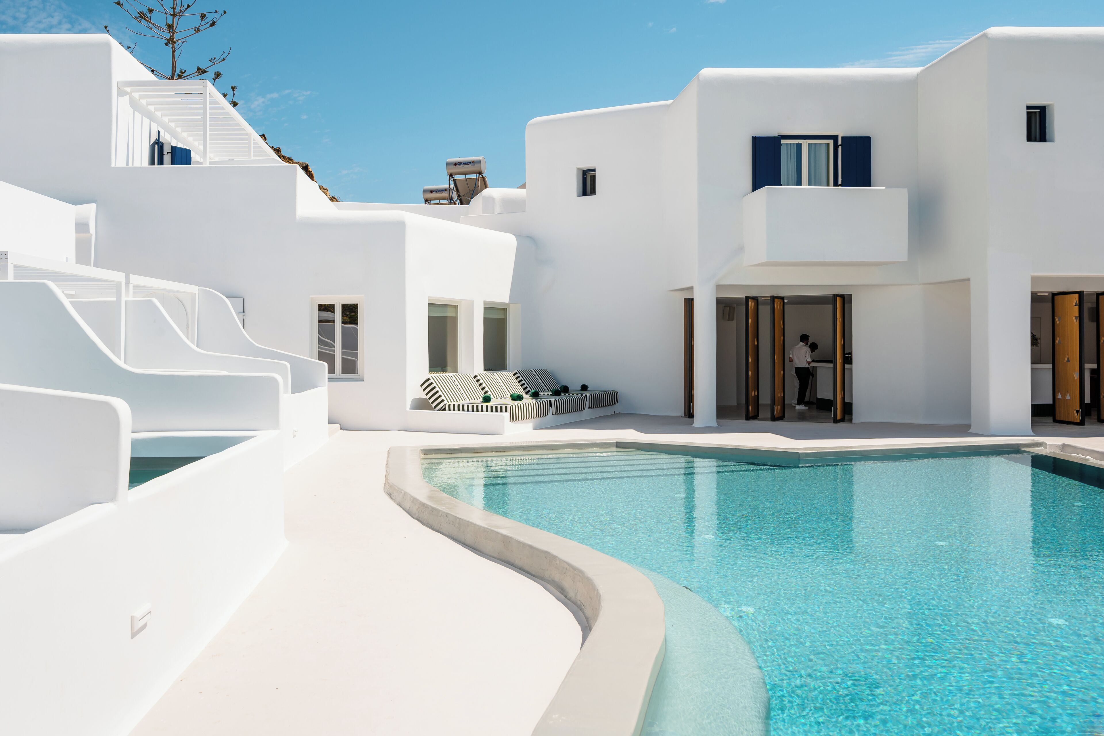 A modern white building with a pool, steps, and lounge chairs.