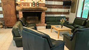 Una sala de estar con chimenea, sofás de cuero, una mesa de centro de madera y un televisor montado en la pared.