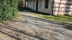 Una casa con camino de grava, un jardín pequeño y un muro de ladrillo.