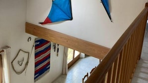 Una escalera con barandilla de madera y un tragaluz arriba.