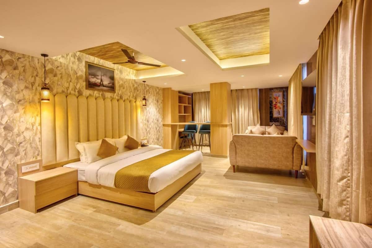A modern hotel room with a large bed, a desk, a sofa, and a ceiling fan.