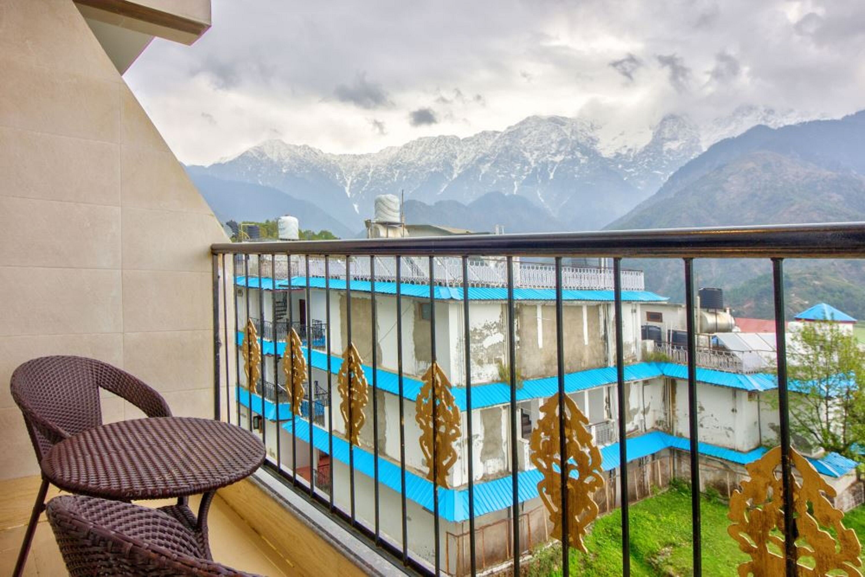 A balcony with a view of mountains, a chair, and a building with blue roofs.