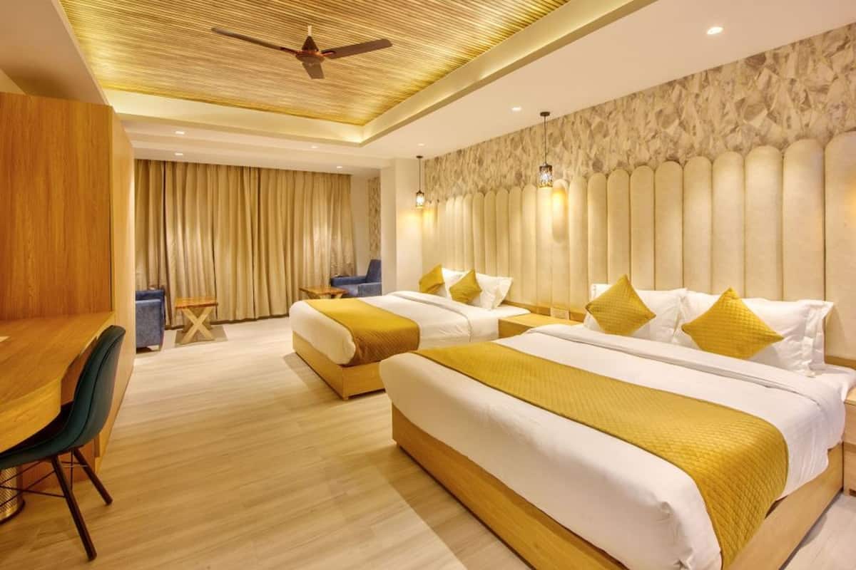 A hotel room with two beds, a dining area, and a ceiling fan.