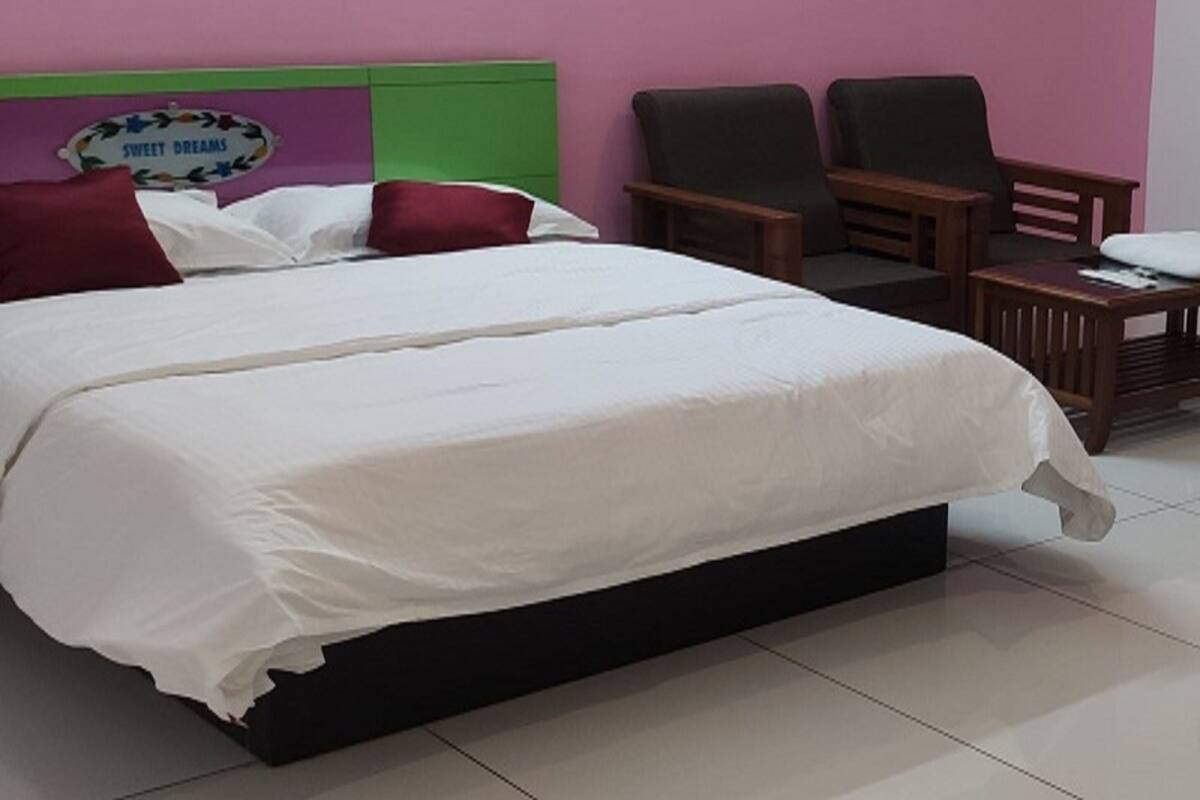 A hotel room with a large bed, two armchairs, a small table, and a wall sign reading "SWEET DREAMS".