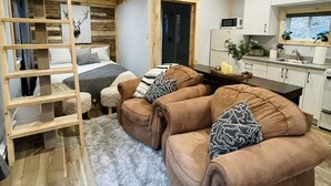 A cozy cabin interior with a loft bed, a sofa set, a kitchen area, and a ceiling fan. - Riverfront Cottage that offer Incredible views, is pet friendly and private (Tatamagouche)