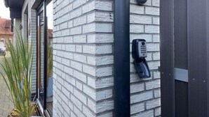 A building with a brick exterior, a black telephone mounted on the wall, and a black pipe running vertically. - Hotel feeling, great location, terrace, BBQ, (Bad Zwischenahn)