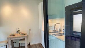 A modern kitchen with a built-in oven, a dining area with a table and chairs, and a large window. - Hotel feeling, great location, terrace, BBQ, (Bad Zwischenahn)