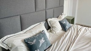 A neatly made bed with a grey upholstered headboard, white bedding, and two pillows with a bird pattern. - Hotel feeling, great location, terrace, BBQ, (Bad Zwischenahn)