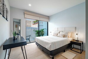 A bedroom with a bed, bedside tables, a desk, and a view through a sliding door.
