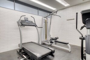 A gym with a treadmill, weight machines, and a bench.