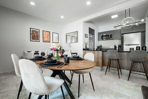 A modern kitchen with a central island, bar stools, and a dining area with a round table and chairs.