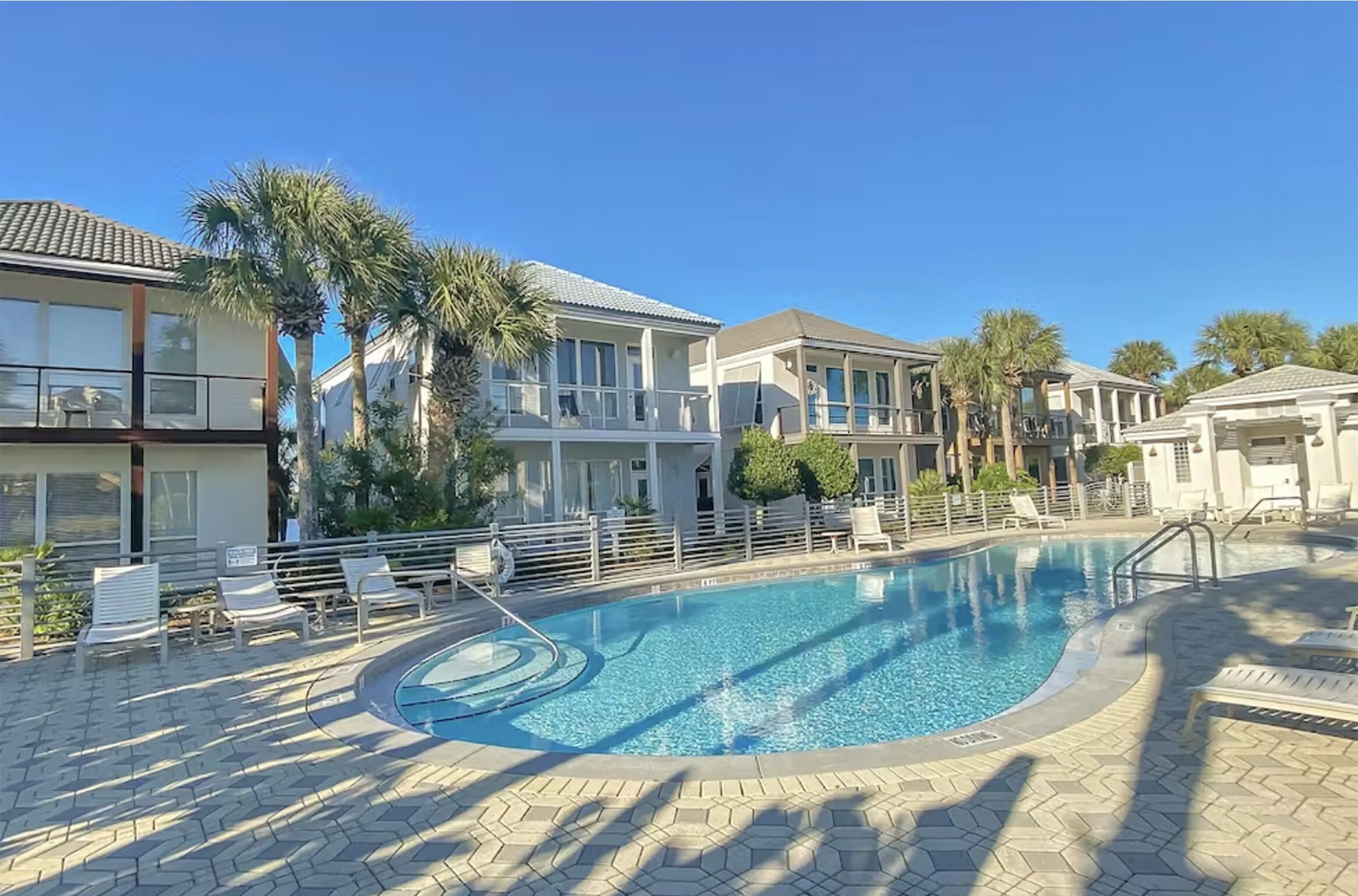 A swimming pool area with lounge chairs and a clear blue sky.