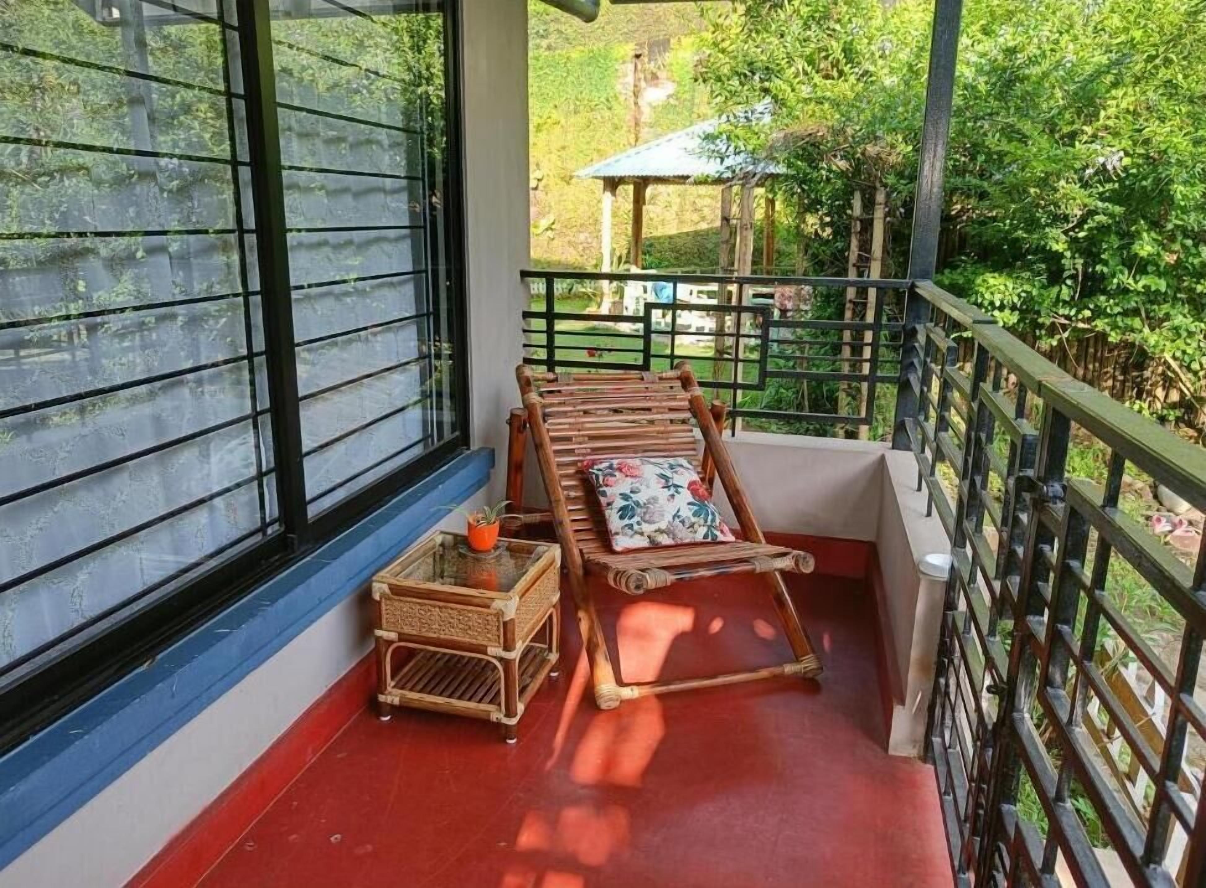A balcony with a wooden chair and a small table with a plant.