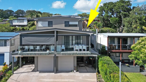 Una casa moderna de dos pisos con balcón, paneles solares y un gran ventanal.