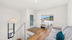 Une chambre d’hôtel moderne avec un escalier, un balcon doté d’un lit et une vue sur l’extérieur.