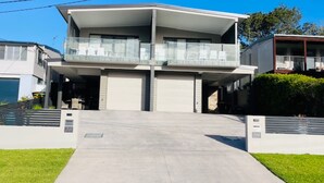 Un immeuble résidentiel à deux étages doté d’un balcon, de portes de garage et d’une allée.