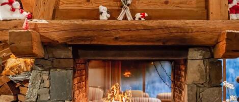 A fireplace with a stone surround, wooden mantel, and two small figurines.
