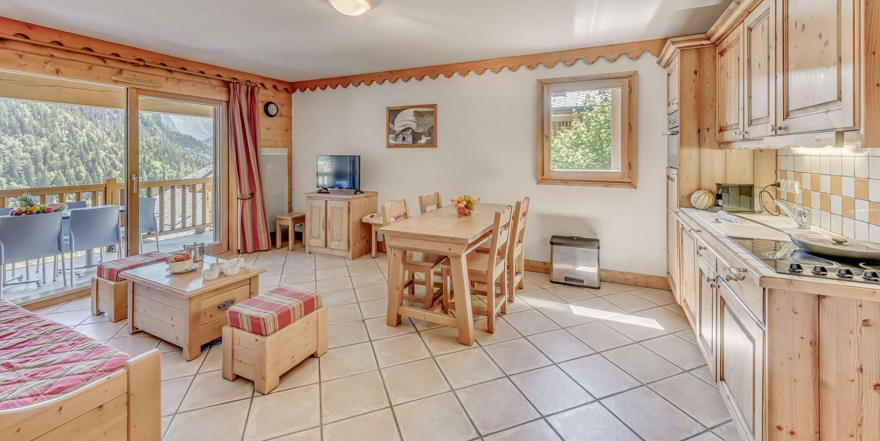 A cozy cabin interior with a dining area, kitchen, and a balcony with a view of the forest.