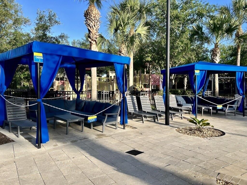 Outdoor seating areas with blue canopies, a palm tree, and a sign indicating 'CABANI 1'.