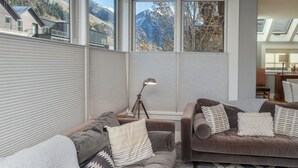 Ett modernt vardagsrum med stora fönster, en soffgrupp och en lampa.