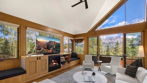 A modern living room with a fireplace, large windows offering mountain views, and comfortable seating. - Slopeside Chalet 4 Bedroom Home by RedAwning (Telluride)