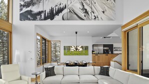 A modern living room with a sectional sofa, a dining area with a table and chairs, and a kitchen in the background. - Slopeside Chalet 4 Bedroom Home by RedAwning (Telluride)