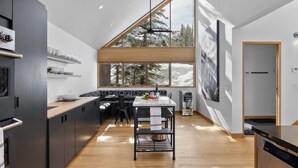 A modern kitchen with a large window, wooden flooring, and a dining area with a central island. - Slopeside Chalet 4 Bedroom Home by RedAwning (Telluride)