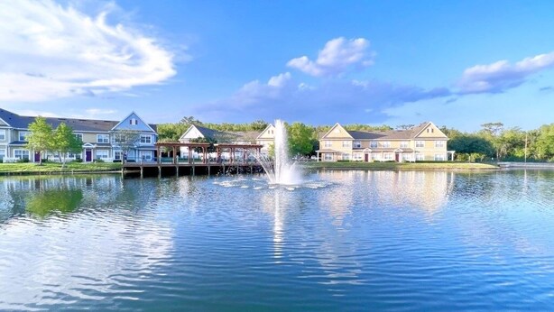 A calm lake with a fountain, surrounded by residential buildings.