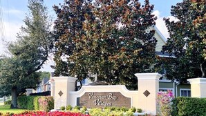 A sign for Venetian Bay Villages with a landscaped garden in front.