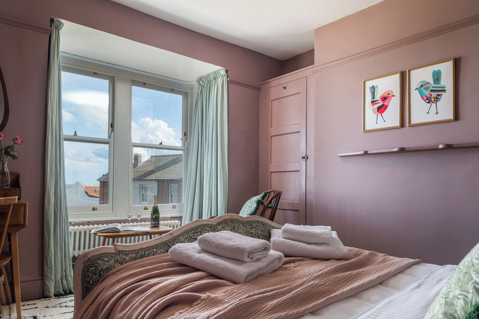A bedroom with a bed, a window, a radiator, and a door.
