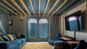 A living room with a blue sofa, ottoman, and a TV on the wall. - Astondene, East Cliff (Reydon)