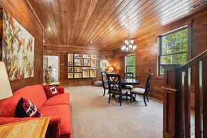 A wooden interior with a dining area, a red sofa, and a chandelier. - Luxury Lodge Sleeps 26 Comfortably at Sapphire Valley Resort (Sapphire)