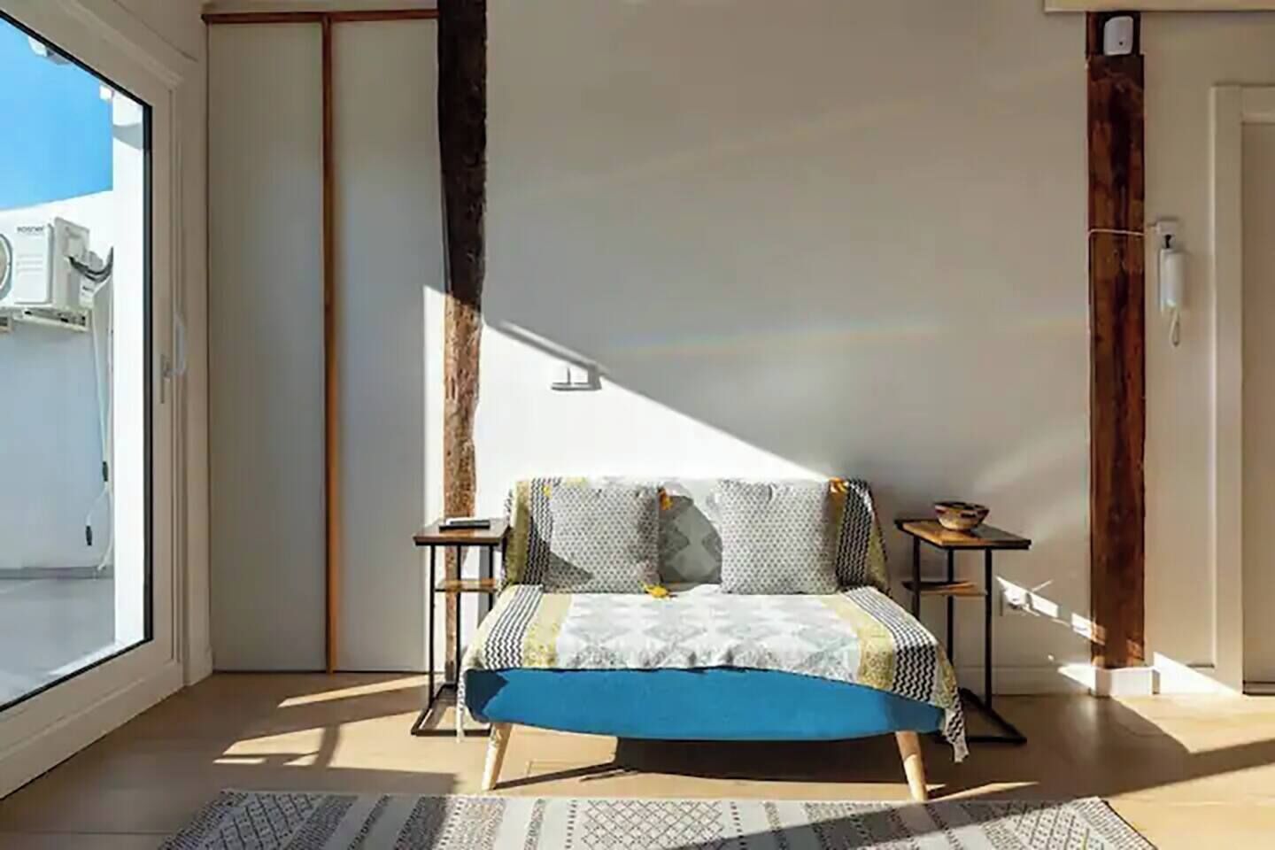 Un dormitorio con cama, mesitas de noche, una ventana y vistas al exterior.