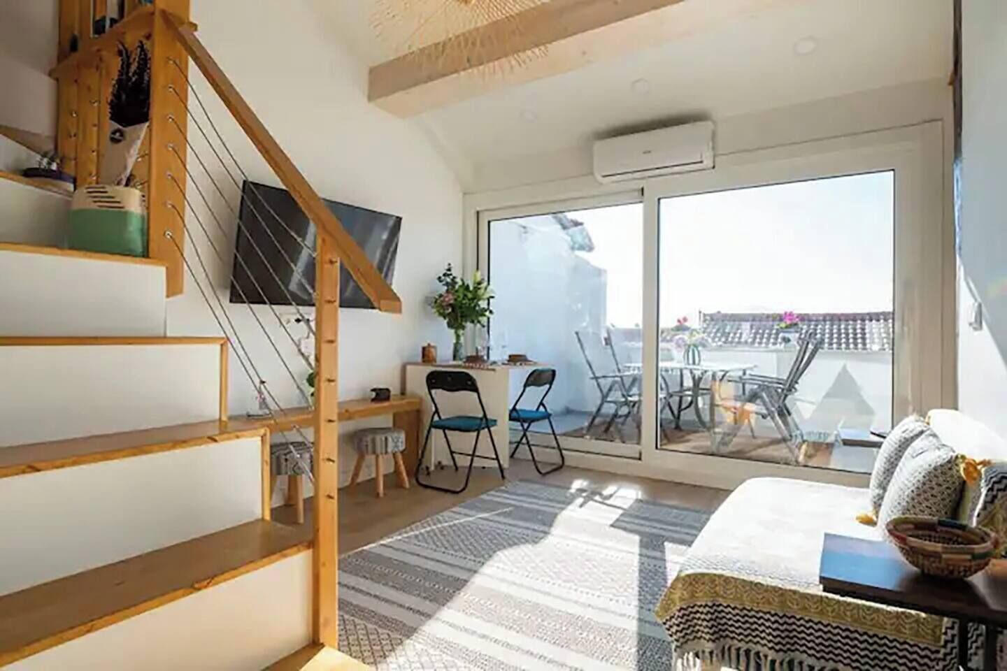 A modern interior with a staircase, a desk, chairs, and a balcony with a view.